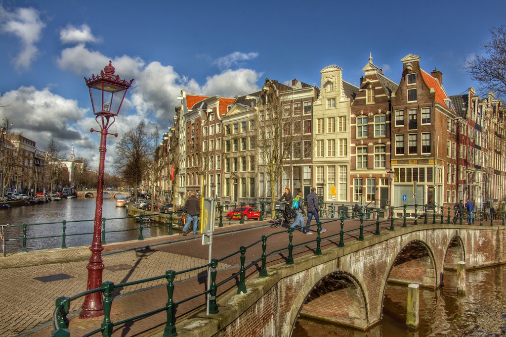 three people walking down a bridge in Amsterdam.